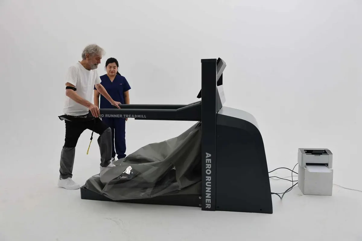 A patient stepping into the AERO RUNNER chamber with a clinician beside him